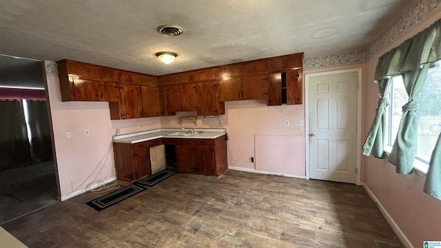 kitchen with visible vents, brown cabinets, dark wood-style floors, light countertops, and baseboards