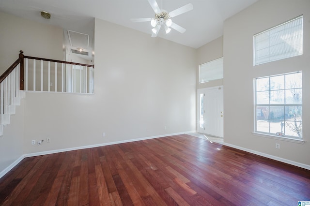 interior space featuring ceiling fan, baseboards, stairway, a high ceiling, and wood finished floors