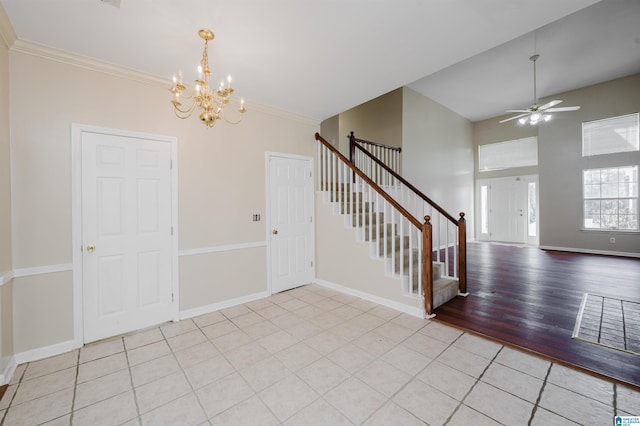 entrance foyer featuring light wood-style flooring, ceiling fan with notable chandelier, crown molding, baseboards, and stairs