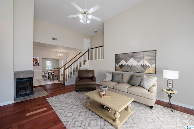 living area with visible vents, baseboards, stairway, ceiling fan with notable chandelier, and wood finished floors