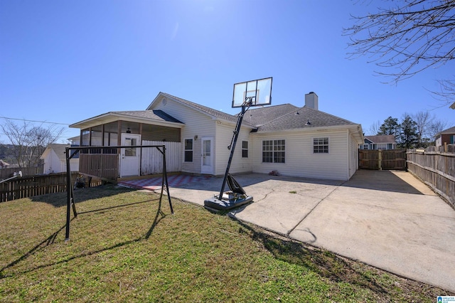 back of property featuring a fenced backyard, a yard, a shingled roof, a chimney, and a patio area