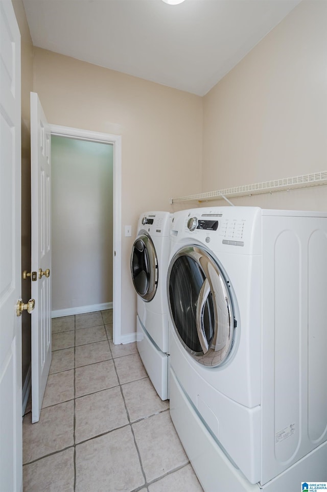 laundry area with light tile patterned floors, baseboards, washing machine and dryer, and laundry area