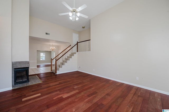 unfurnished living room featuring visible vents, wood finished floors, stairs, and a tile fireplace