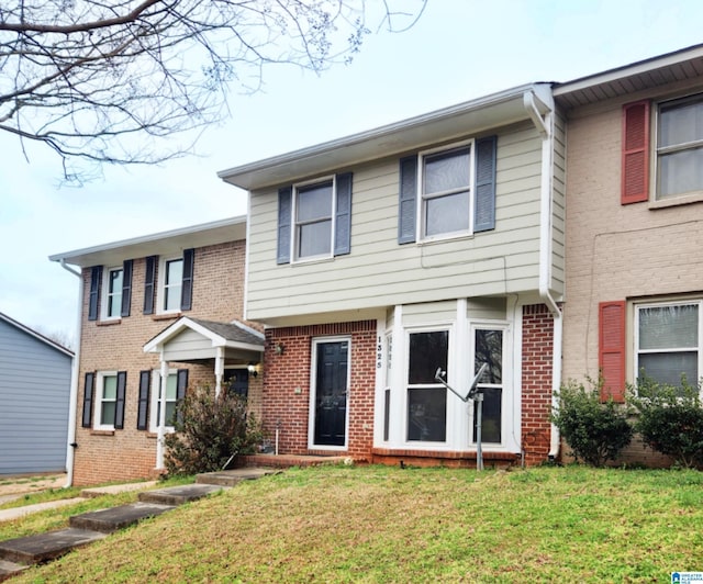 multi unit property with a front lawn and brick siding