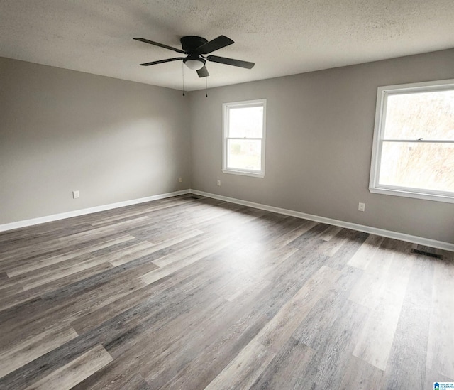 unfurnished room featuring wood finished floors, visible vents, and baseboards