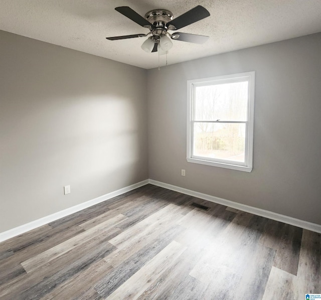 unfurnished room featuring visible vents, a textured ceiling, wood finished floors, baseboards, and ceiling fan