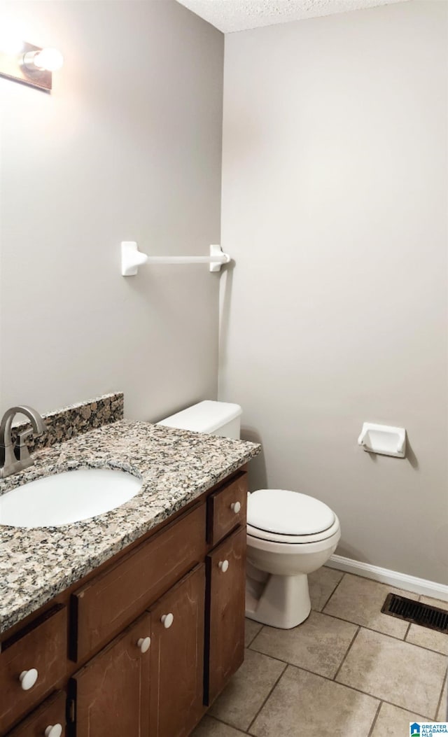 bathroom featuring tile patterned flooring, visible vents, toilet, vanity, and a textured ceiling