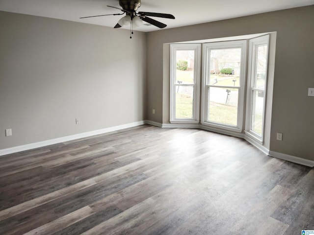 empty room featuring baseboards, wood finished floors, and a ceiling fan