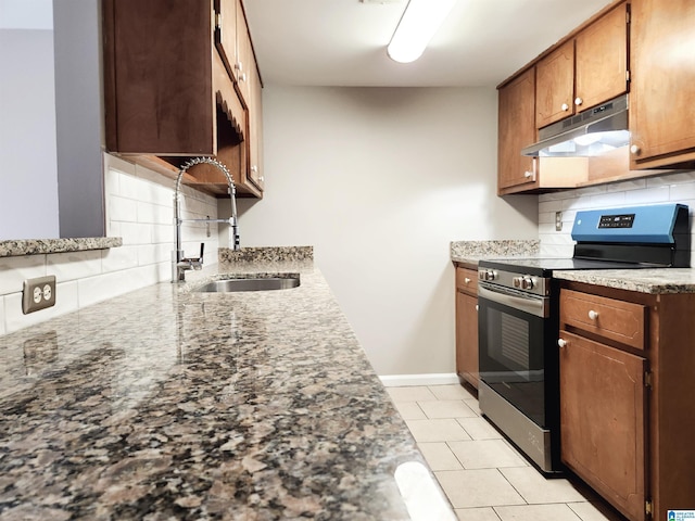 kitchen featuring electric stove, under cabinet range hood, a sink, decorative backsplash, and baseboards