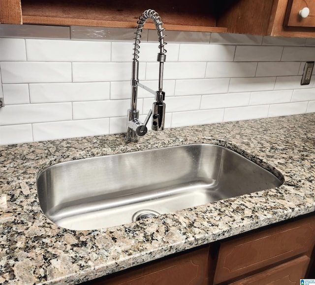 details with backsplash, light stone countertops, and a sink