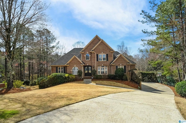 view of front facade featuring brick siding, driveway, and a front yard