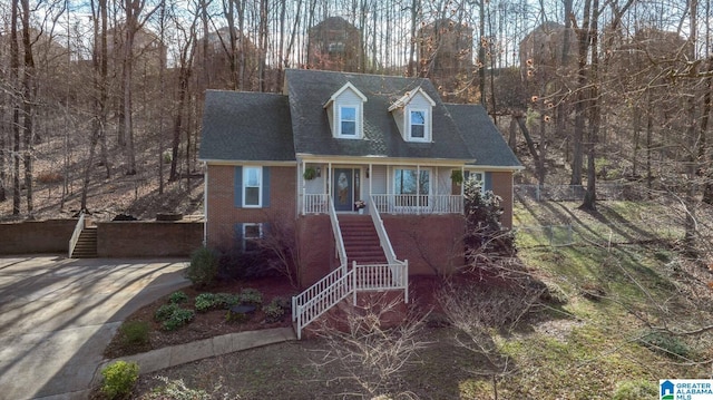 cape cod-style house with a porch, stairway, and brick siding