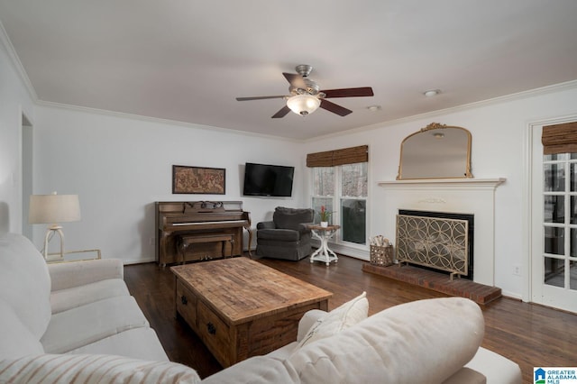 living room with ceiling fan, a fireplace, wood finished floors, and crown molding