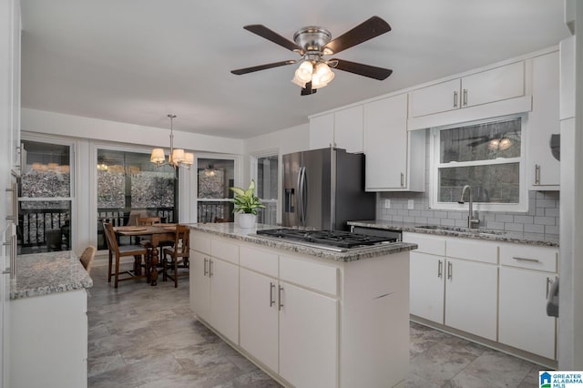 kitchen featuring backsplash, a center island, stainless steel appliances, white cabinetry, and a sink