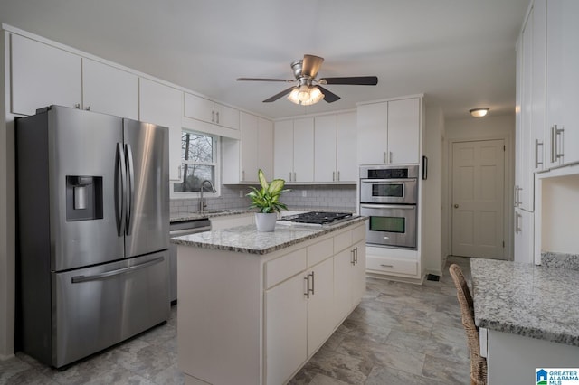 kitchen with a ceiling fan, tasteful backsplash, light stone countertops, and stainless steel appliances