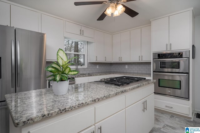 kitchen with tasteful backsplash, stainless steel appliances, a ceiling fan, and a sink