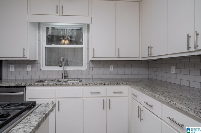 kitchen featuring a sink, tasteful backsplash, white cabinets, and stainless steel gas cooktop