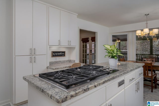 kitchen with stainless steel gas cooktop, a notable chandelier, white cabinetry, and hanging light fixtures