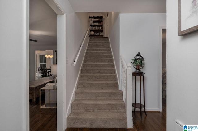 stairs featuring a notable chandelier and wood finished floors