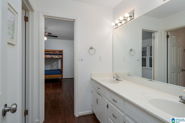 ensuite bathroom featuring double vanity, wood finished floors, ceiling fan, and a sink