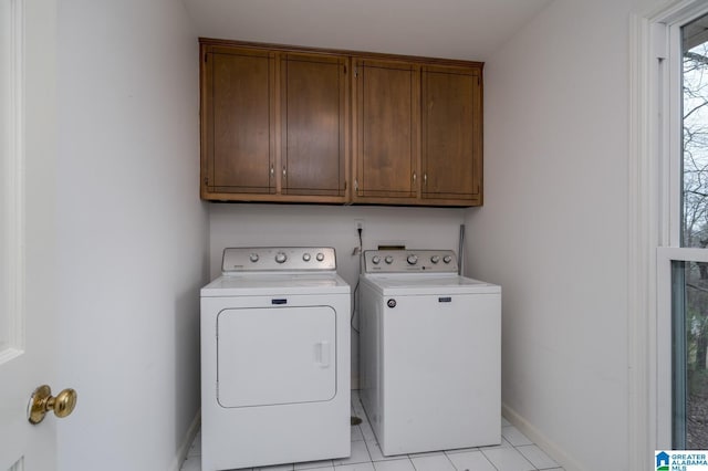 washroom featuring washing machine and clothes dryer, cabinet space, and baseboards