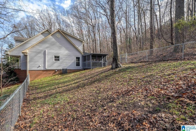 exterior space with central AC, a fenced backyard, and a sunroom