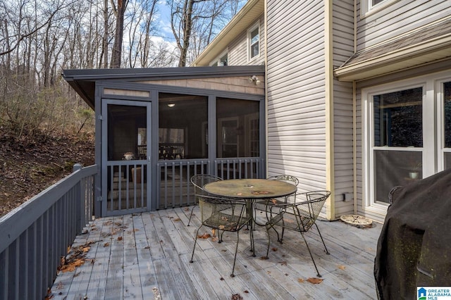 deck with outdoor dining space, a sunroom, and grilling area