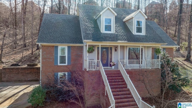 view of front of house with brick siding, stairway, a porch, and a shingled roof