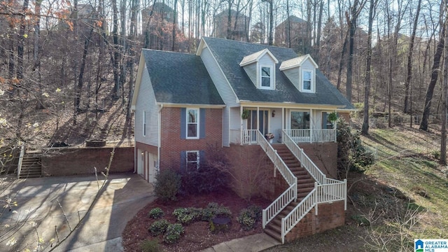 view of front facade with brick siding, stairway, a porch, concrete driveway, and a garage