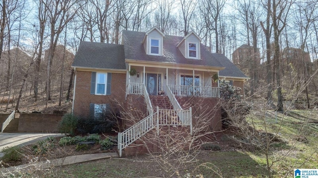 new england style home with brick siding, stairway, a porch, and roof with shingles