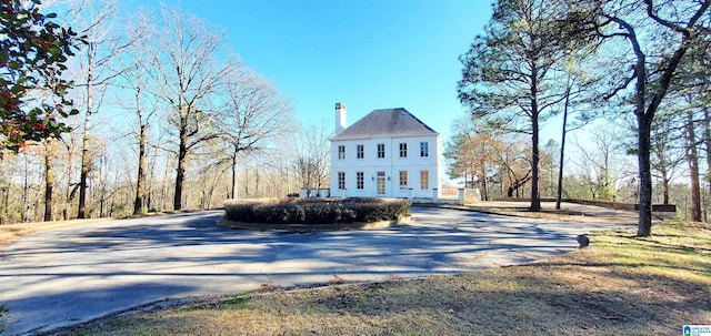 view of property exterior with driveway and a chimney