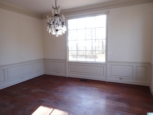 unfurnished room featuring crown molding, a decorative wall, wood finished floors, and visible vents