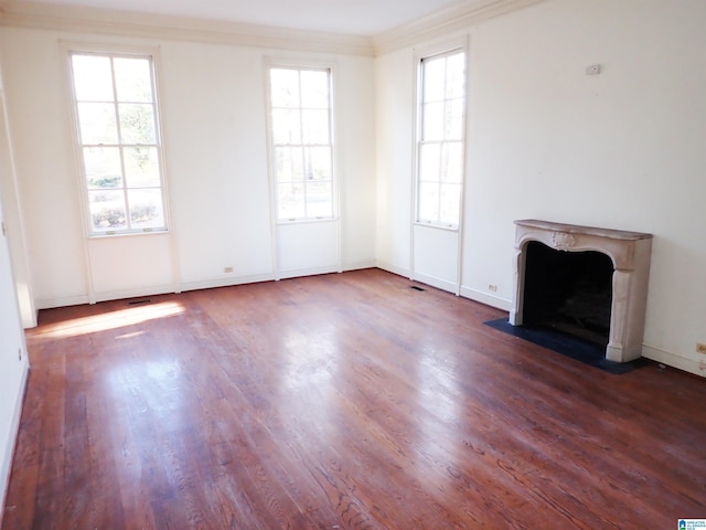 unfurnished living room with visible vents, ornamental molding, wood finished floors, a premium fireplace, and baseboards