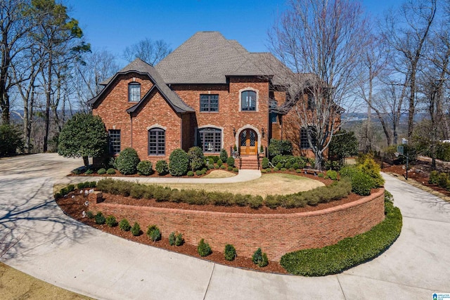 view of front facade featuring concrete driveway, brick siding, and a shingled roof