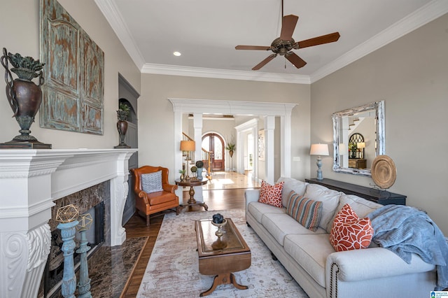 living area featuring ceiling fan, a premium fireplace, wood finished floors, and ornamental molding