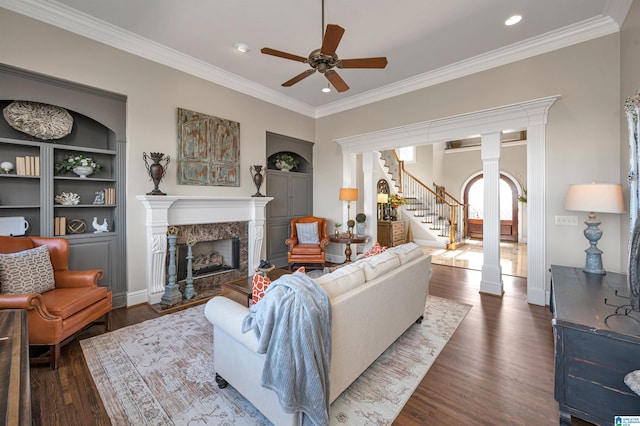 living area featuring a high end fireplace, stairs, ornate columns, and wood finished floors