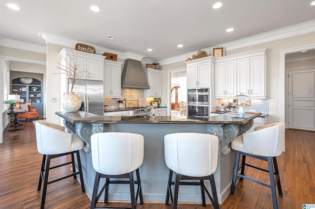 kitchen featuring dark countertops, appliances with stainless steel finishes, dark wood-style floors, and custom range hood