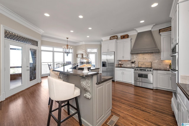 kitchen with dark countertops, white cabinets, premium range hood, and appliances with stainless steel finishes