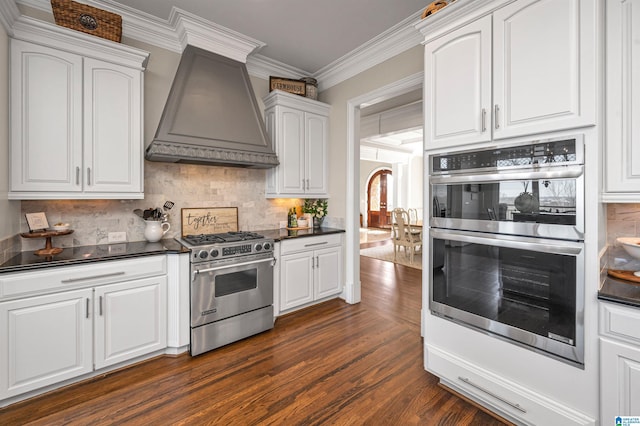 kitchen with premium range hood, dark wood finished floors, white cabinets, appliances with stainless steel finishes, and dark countertops