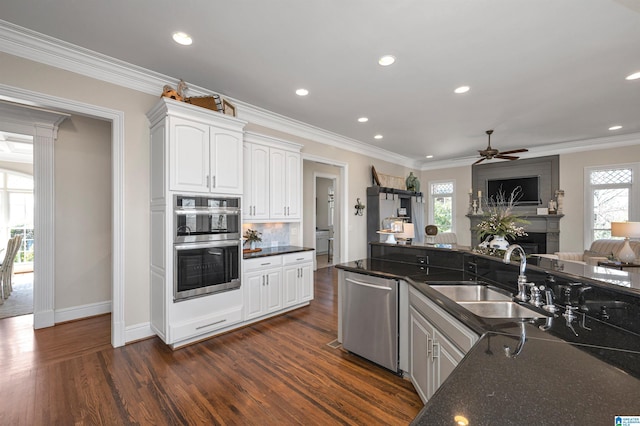 kitchen featuring a large fireplace, dark wood-type flooring, open floor plan, appliances with stainless steel finishes, and a sink