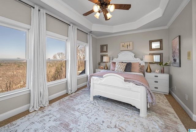 carpeted bedroom with ceiling fan, a raised ceiling, baseboards, and ornamental molding