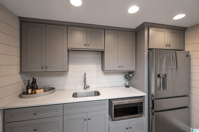 kitchen featuring gray cabinets, appliances with stainless steel finishes, light countertops, and a sink