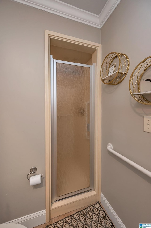 bathroom with baseboards, ornamental molding, and a shower stall