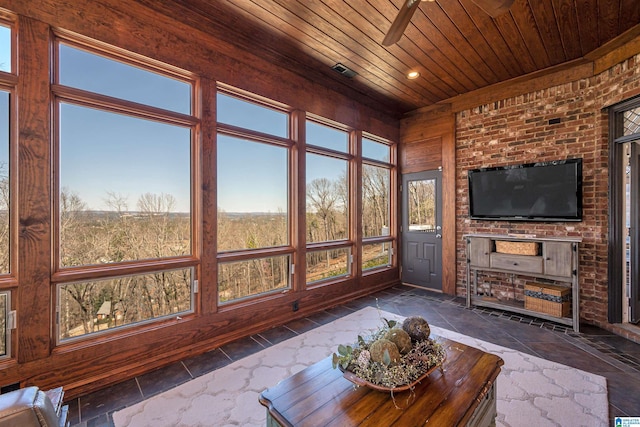 unfurnished sunroom featuring wooden ceiling, visible vents, a wealth of natural light, and ceiling fan