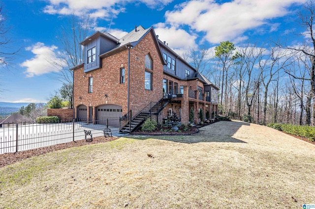 view of side of home featuring driveway, fence, a garage, brick siding, and stairs