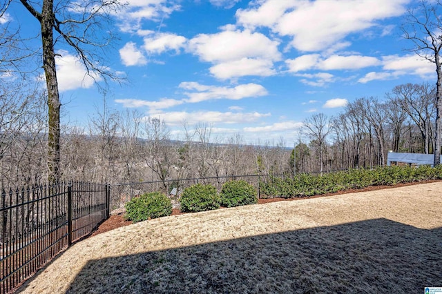 view of yard featuring fence and a wooded view