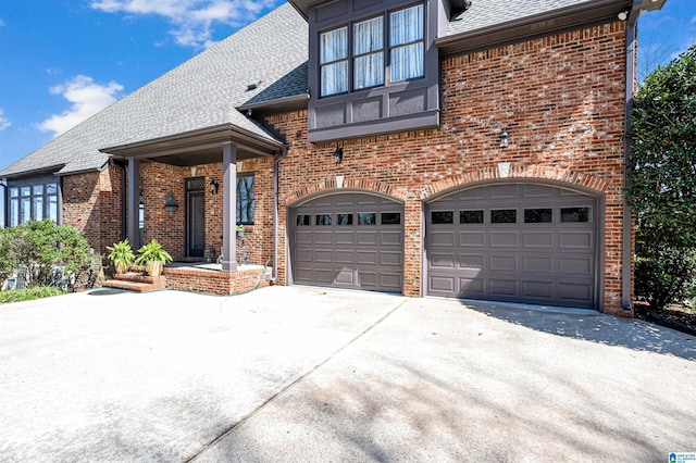 view of front of house with brick siding, driveway, a shingled roof, and an attached garage