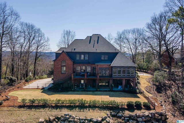 rear view of house with brick siding, fence private yard, a yard, a sunroom, and a patio