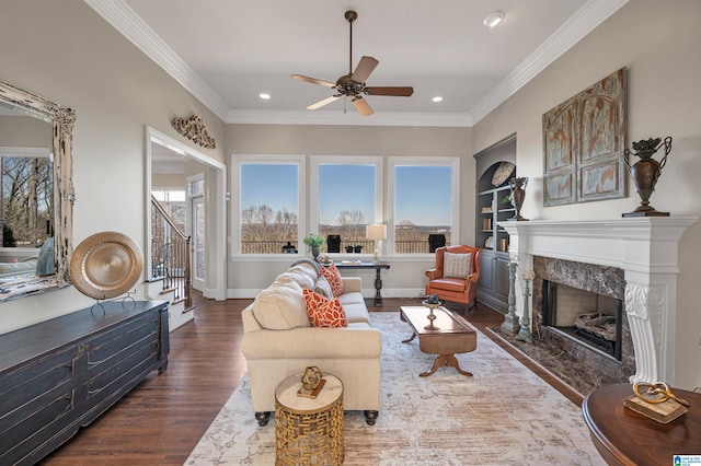 living area featuring a fireplace, wood finished floors, baseboards, and ornamental molding