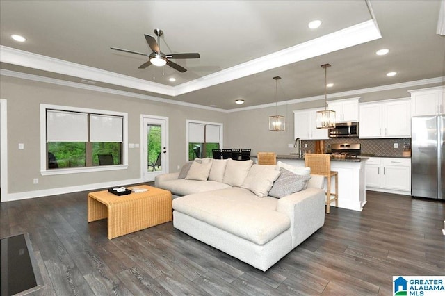 living room with ceiling fan with notable chandelier, a raised ceiling, recessed lighting, and dark wood-type flooring